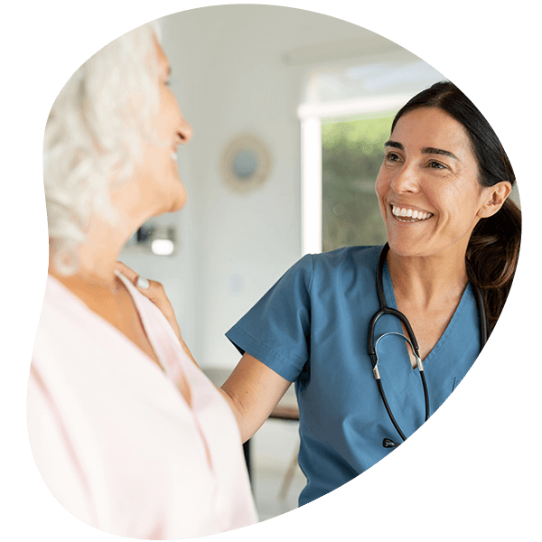 Happy doctor talking to a senior woman on a house call and smiling